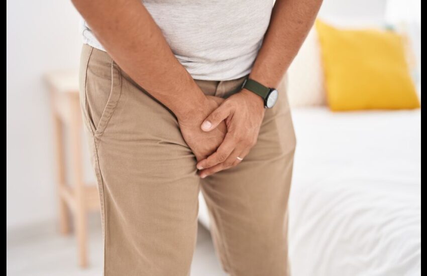 A man with a worried expression, holding his penis, reflecting concerns about misconceptions surrounding creatine use.