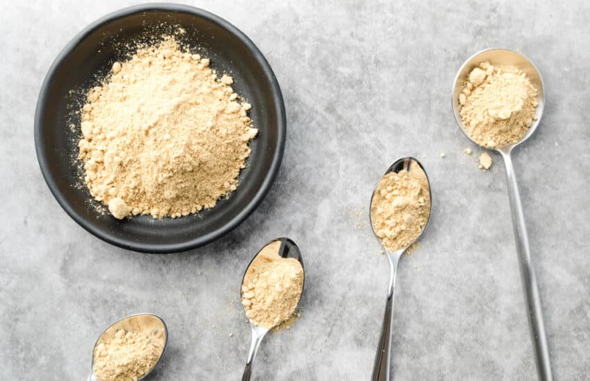 A bowl of powder and spoons on a table, highlighting dry scoop creatine, an unsafe practice with no scientific benefits.